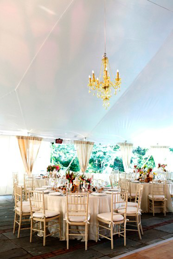 round table seating in a tented reception area - gold chandelier - charming Hudson Valley NY wedding photo by top New York wedding photographers Belathee Photography